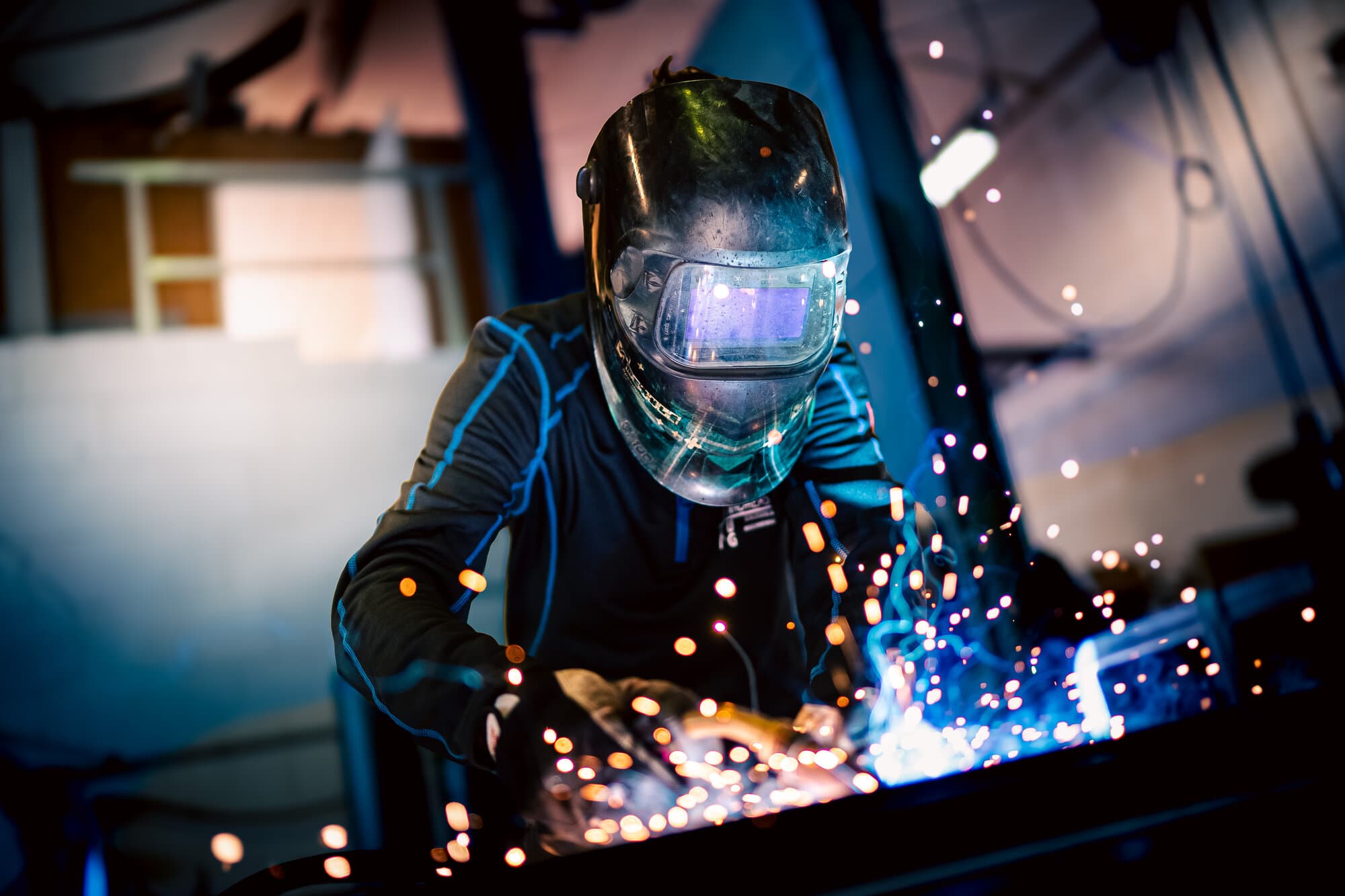 Schweißer der Haug GmbH beim Schutzgasschweißen mit Funkenflug in der Werkstatt